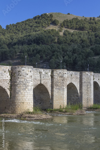 Old stone bridge block with arches and water