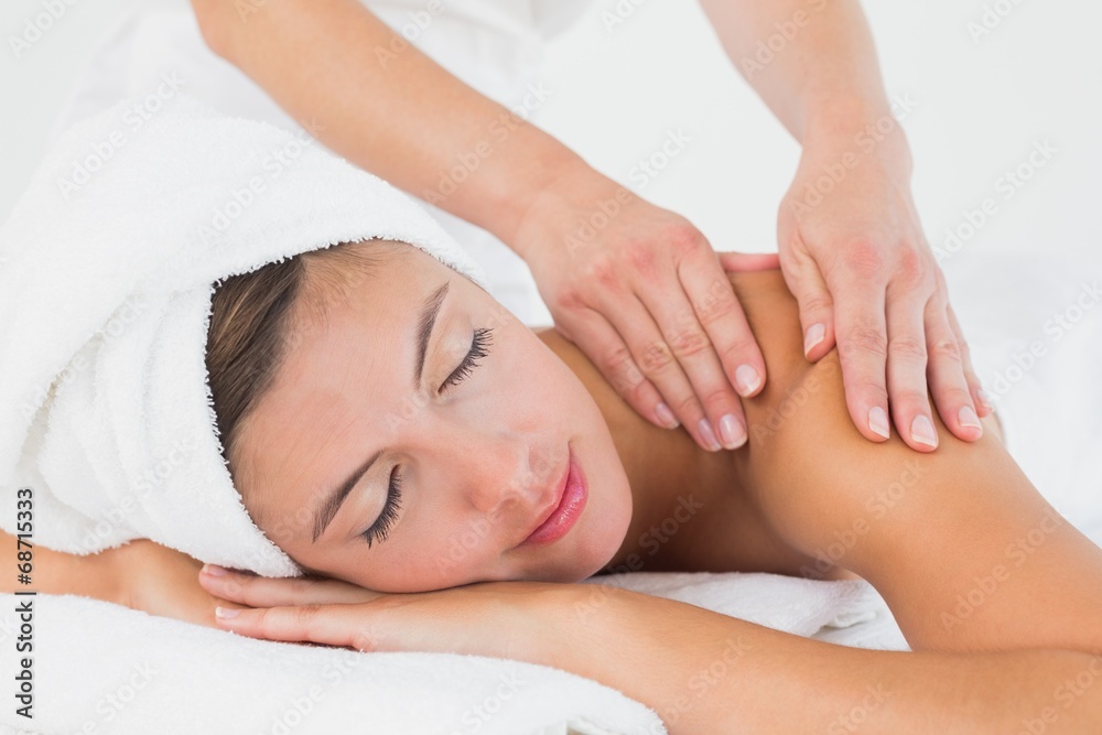 Attractive young woman receiving shoulder massage at spa center