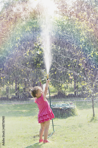 Dziewczynka w różowej sukience oblewająca się wodą