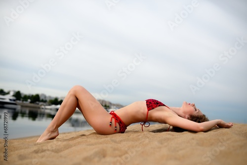 Young woman with curling hair lies on a beach