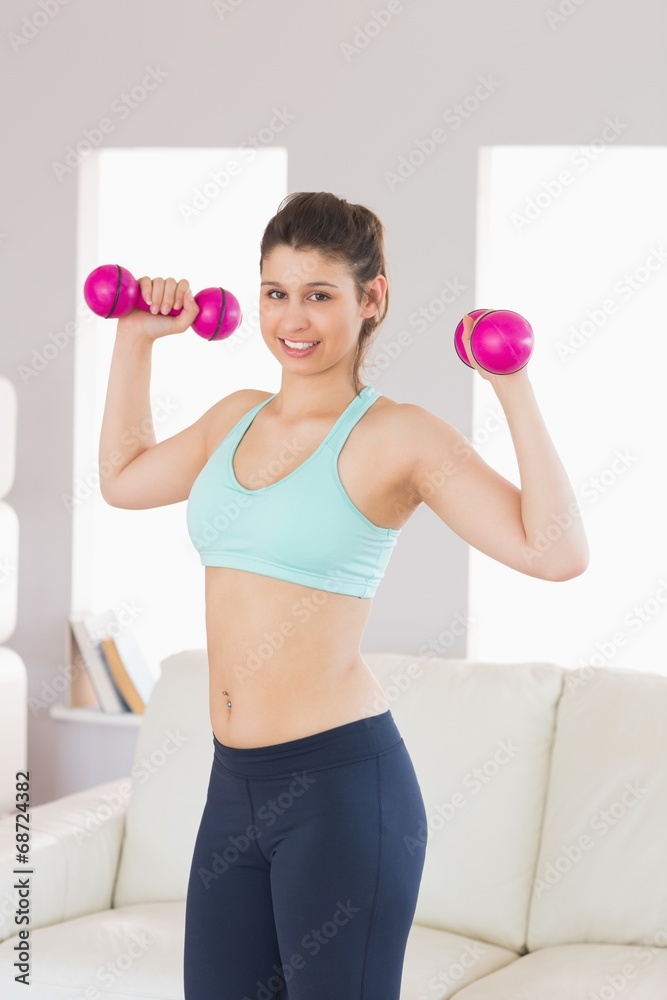 Fit brunette holding dumbbells smiling at camera Fit brunette holding dumbbells smiling at camera