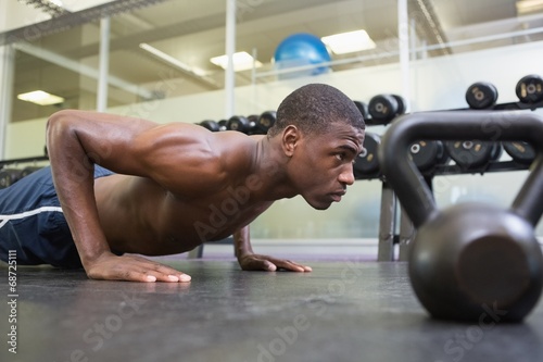 Shirtless muscular man doing push ups in gym