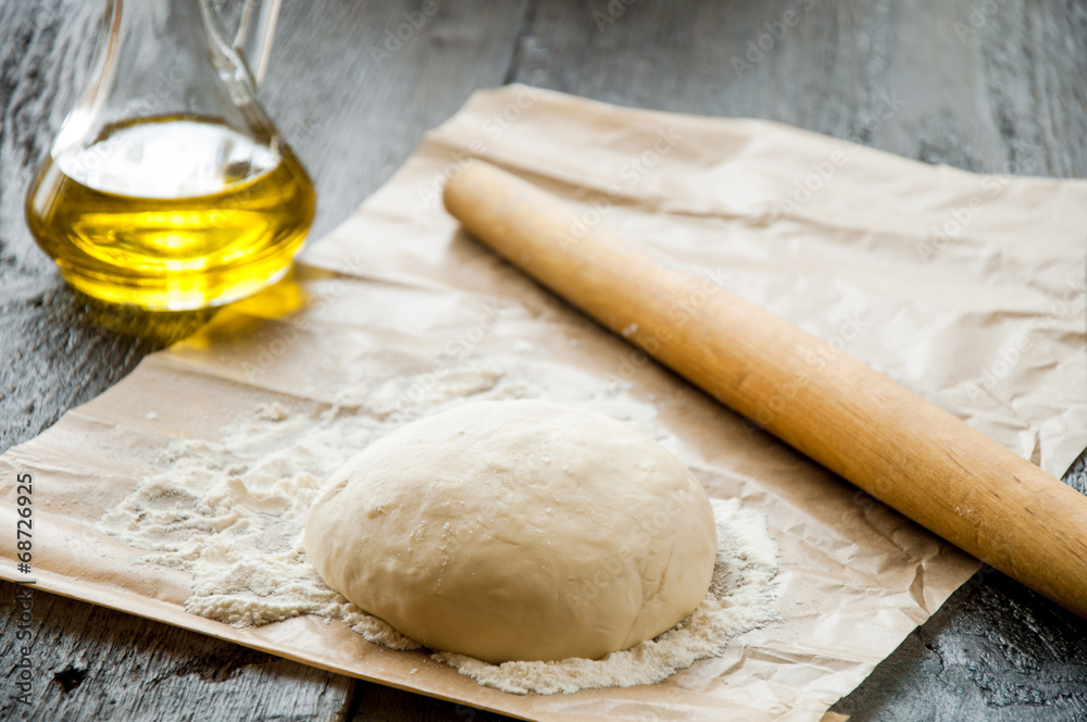 wooden rolling pin with freshly prepared dough for pizza wooden rolling pin with freshly prepared dough for pizza