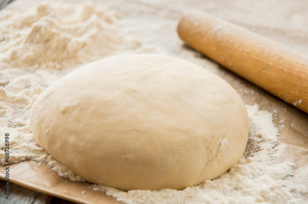 wooden rolling pin with freshly prepared dough for pizza wooden rolling pin with freshly prepared dough for pizza