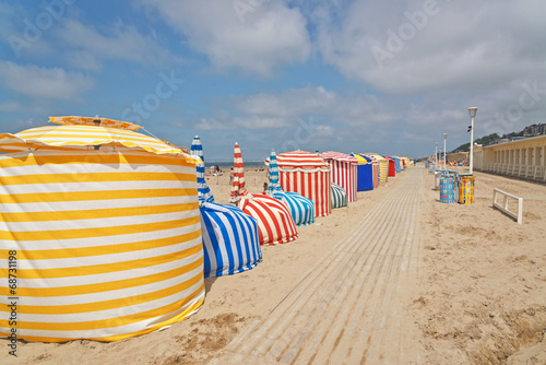 Colored umbrellas at the beach of Deauville with blue cloud sky.