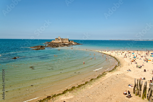 Beach of Saint Malo with fortress and tourists. Blue sky. Britta