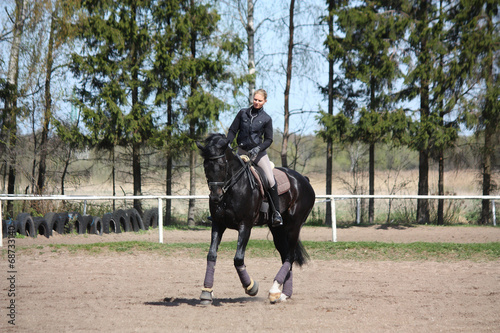Blonde woman riding black horse
