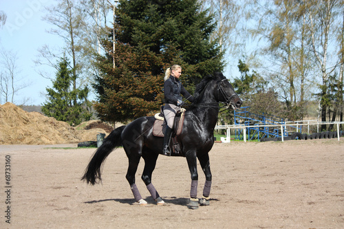 Blonde woman riding black horse © virgonira