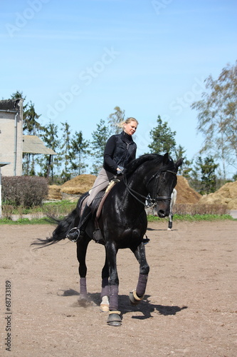 Blonde woman riding black horse © virgonira