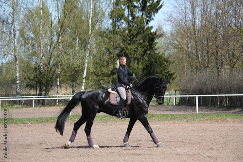 Young woman riding black horse