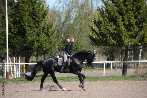 Young woman riding black horse © virgonira