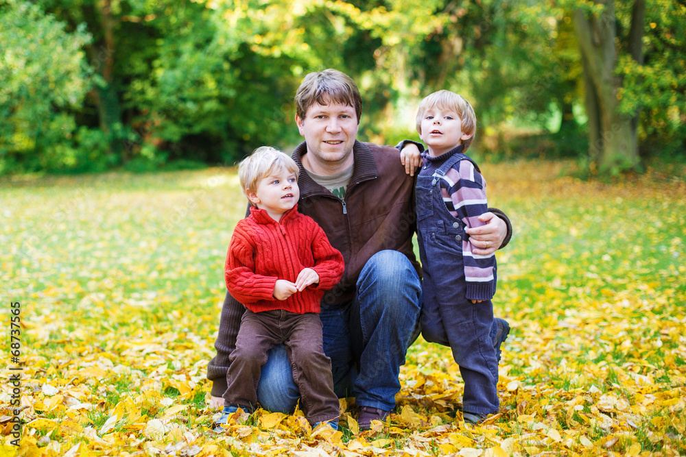 Happy dad with his little sons having fun on sunny autumn day in Happy dad with his little sons having fun on sunny autumn day in