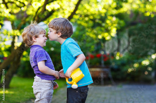 Two little sibling boys hugging and having fun outdoors