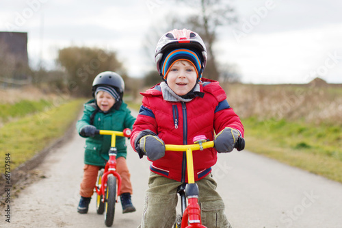 Two little twin toddler boys having fun on bicycles, outdoors