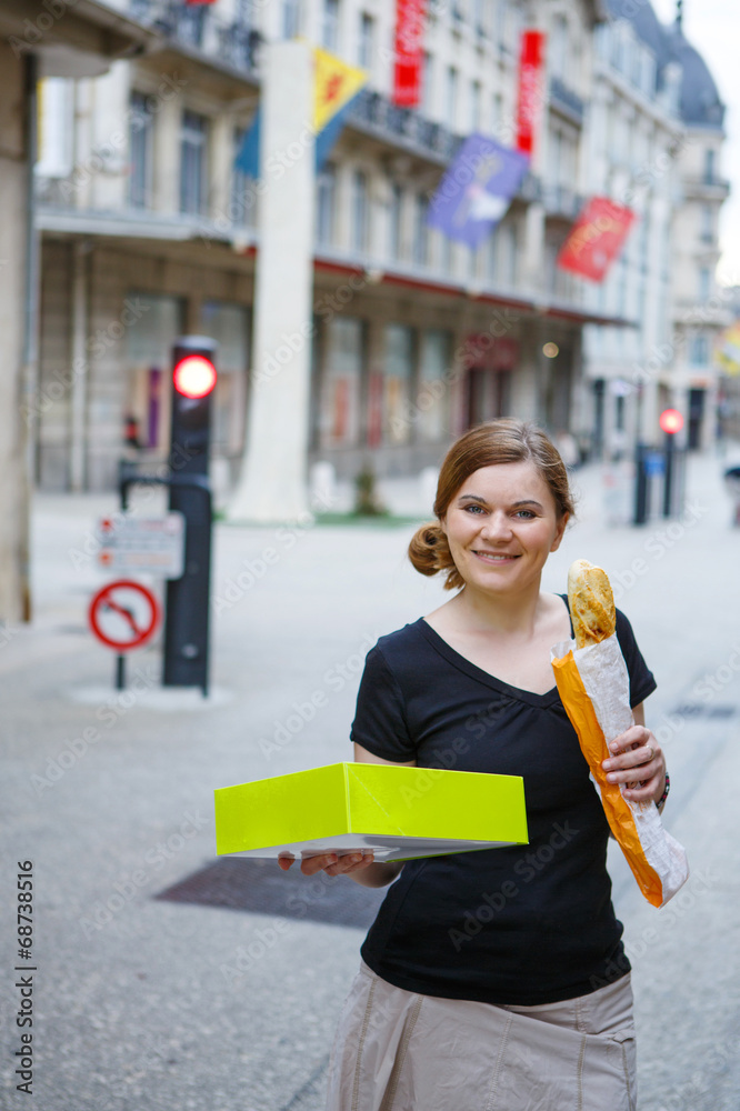 Young woman with fresh baguette on street of a city in France.