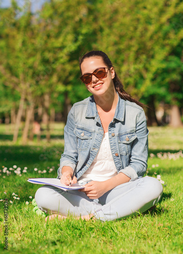 smiling young girl with notebook writing in park