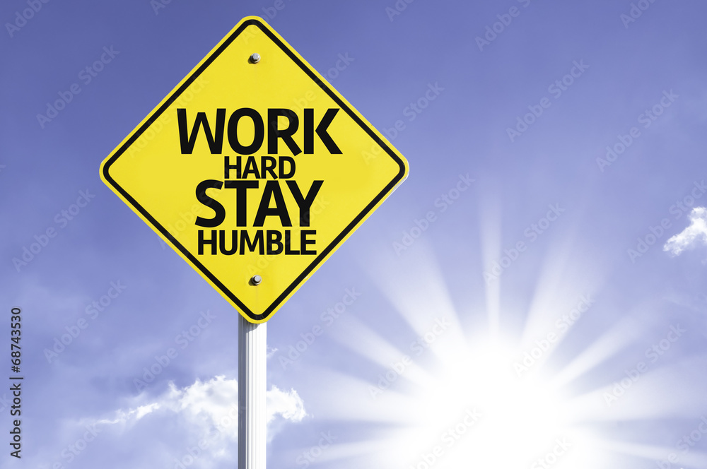 Work Hard, Stay Humble road sign with sun background Work Hard, Stay Humble road sign with sun background