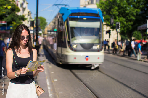 Young beautiful traveling woman with map of city in hands