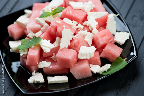 Watermelon and feta cheese salad on a black glass plate