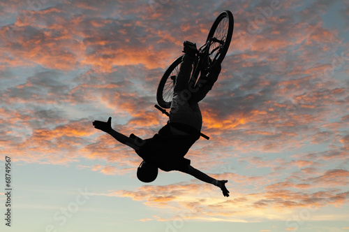 Silhouette bmx sport rider in action with scenery background