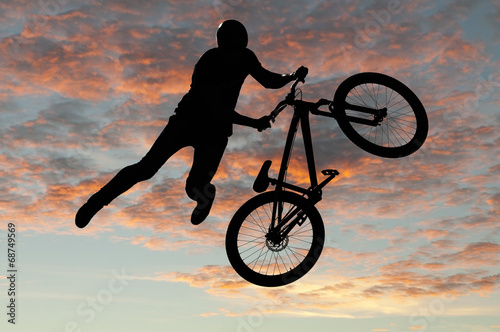 Silhouette bmx sport rider in action with scenery background