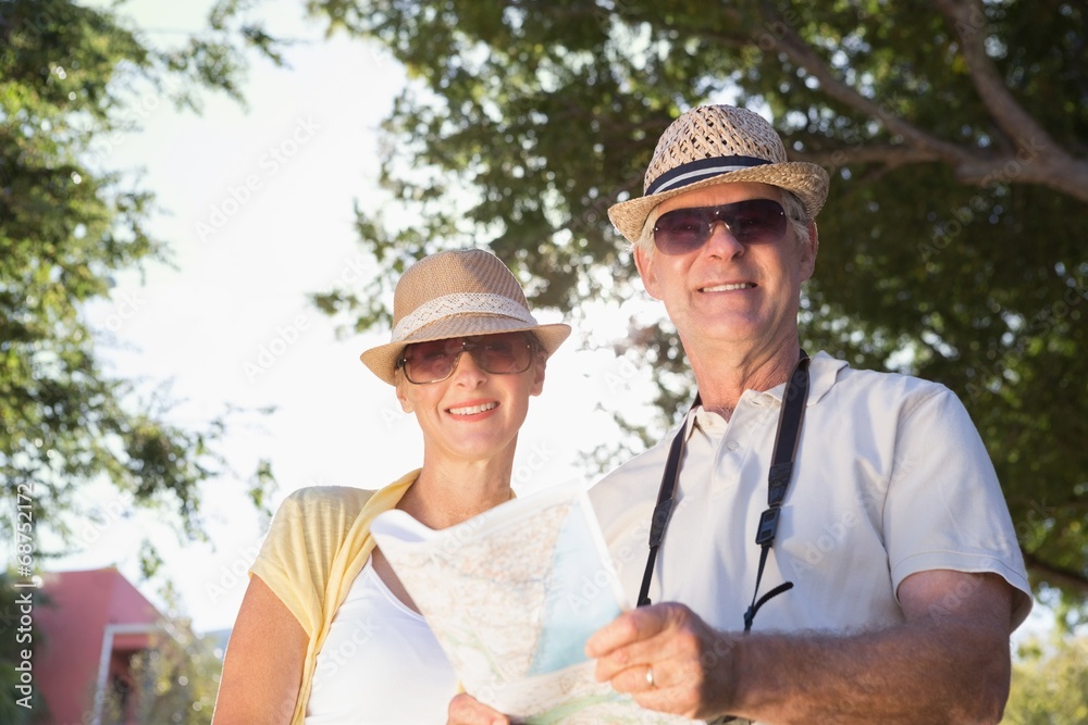 Happy senior couple using the map and looking at camera Happy senior couple using the map and looking at camera