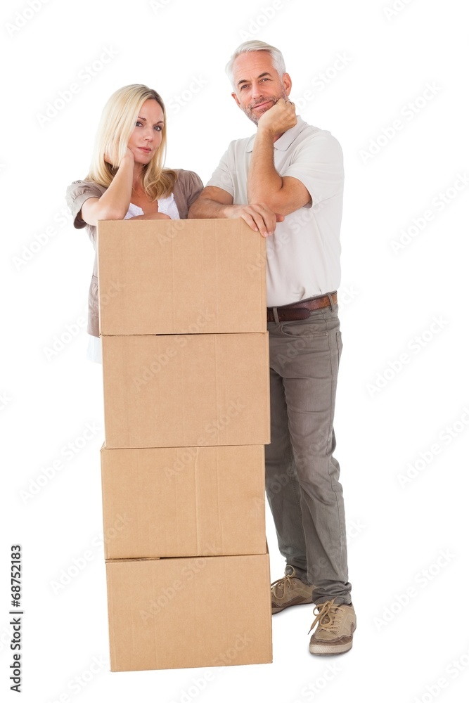 Happy couple leaning on pile of moving boxes Happy couple leaning on pile of moving boxes