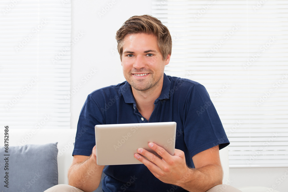 Man Using Digital Tablet On Sofa At Home Man Using Digital Tablet On Sofa At Home