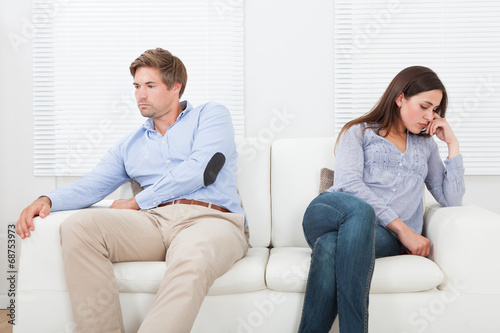 Couple Ignoring Each Other On Sofa