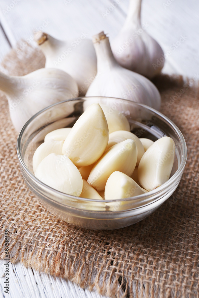 Fresh sliced garlic in glass bowl on wooden background Fresh sliced garlic in glass bowl on wooden background