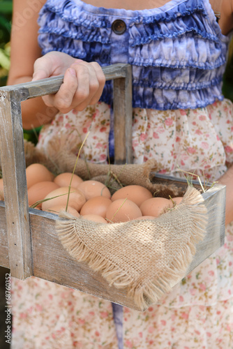 Eggs in wooden basket in female hands outdoors