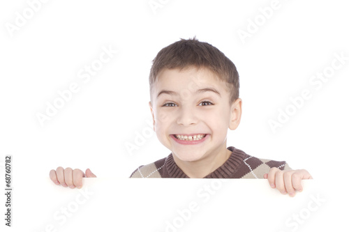 Young boy hiding behind a billboard and making a face on camera