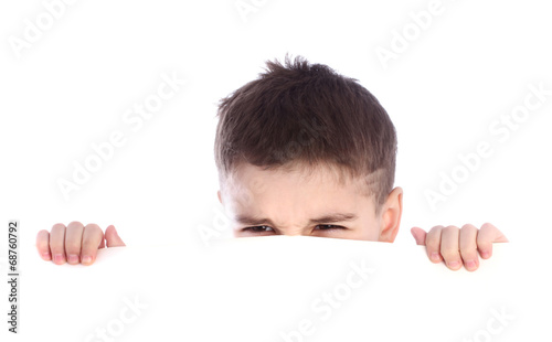 Young boy hiding behind a billboard and making a face isolated o
