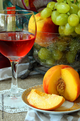 A glass of rose wine, peaches and grapes.