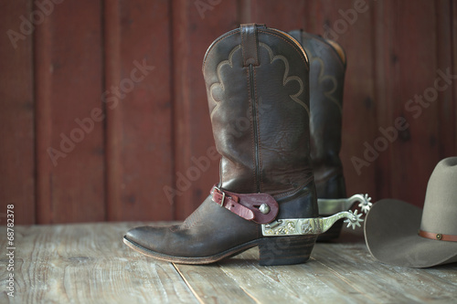 Cowboy boots, spurs and hat on old wood background