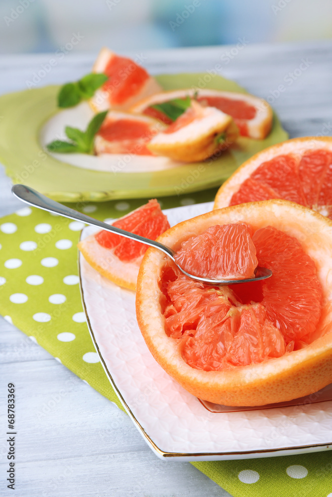 Ripe grapefruits on plate, on wooden table, on light background Ripe grapefruits on plate, on wooden table, on light background