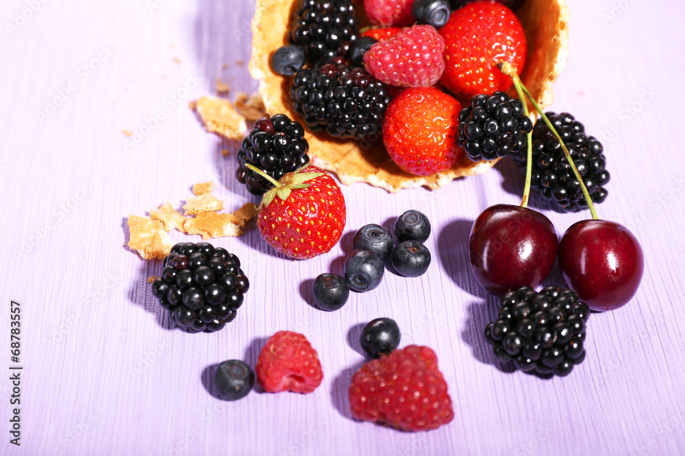 Different ripe berries in sugar cone, on purple background Different ripe berries in sugar cone, on purple background