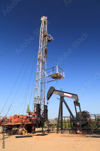 Oil Pump Jack (Sucker Rod Beam) and Workover Rig on Sunny Day photo