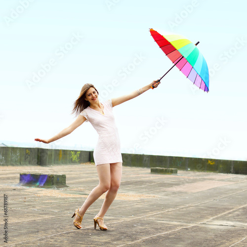Beautiful attractive girl with an umbrella flies from the roof