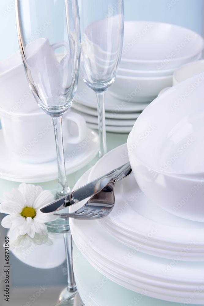 Set of white dishes on table on light background Set of white dishes on table on light background