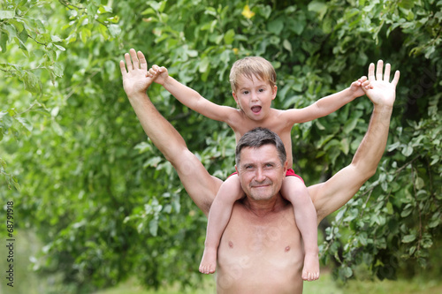  boy sitting on the shoulders of a man stretched hands on a bac