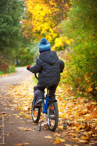A boy is riding on a bike in autumn day