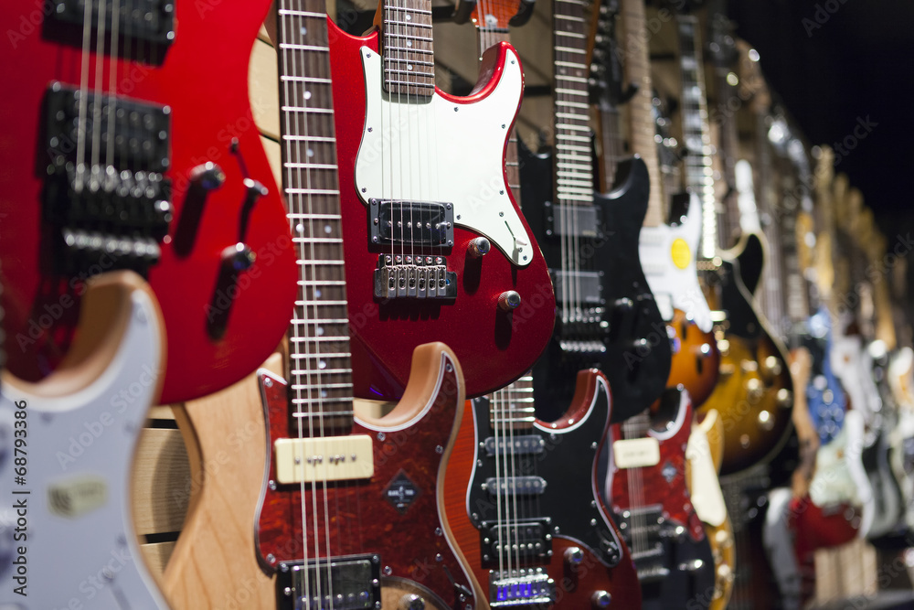 Naklejka premium Wiele gitar elektrycznych wisi na ścianie w sklepie.