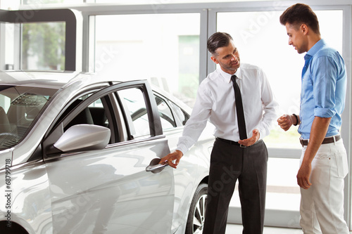 Car Showroom. Vehicle Dealer Showing Young Man New Car © puhhha