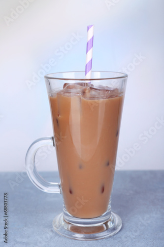Glass of iced milk coffee on light background