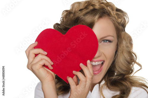Smiling young woman holding heart in front of eye