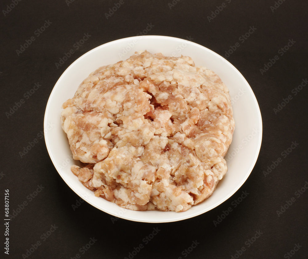 Minced pork meat in the white bow on the black background Minced pork meat in the white bow on the black background