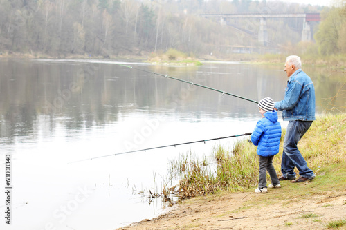 Grandfather and grandson are fishing photo