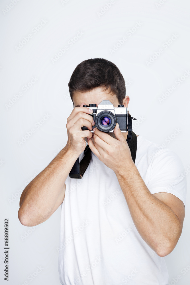 Young man using a retro camera against gray background Young man using a retro camera against gray background