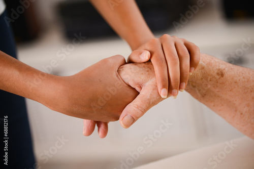 young woman's hands holding tenderly hand of elderly person